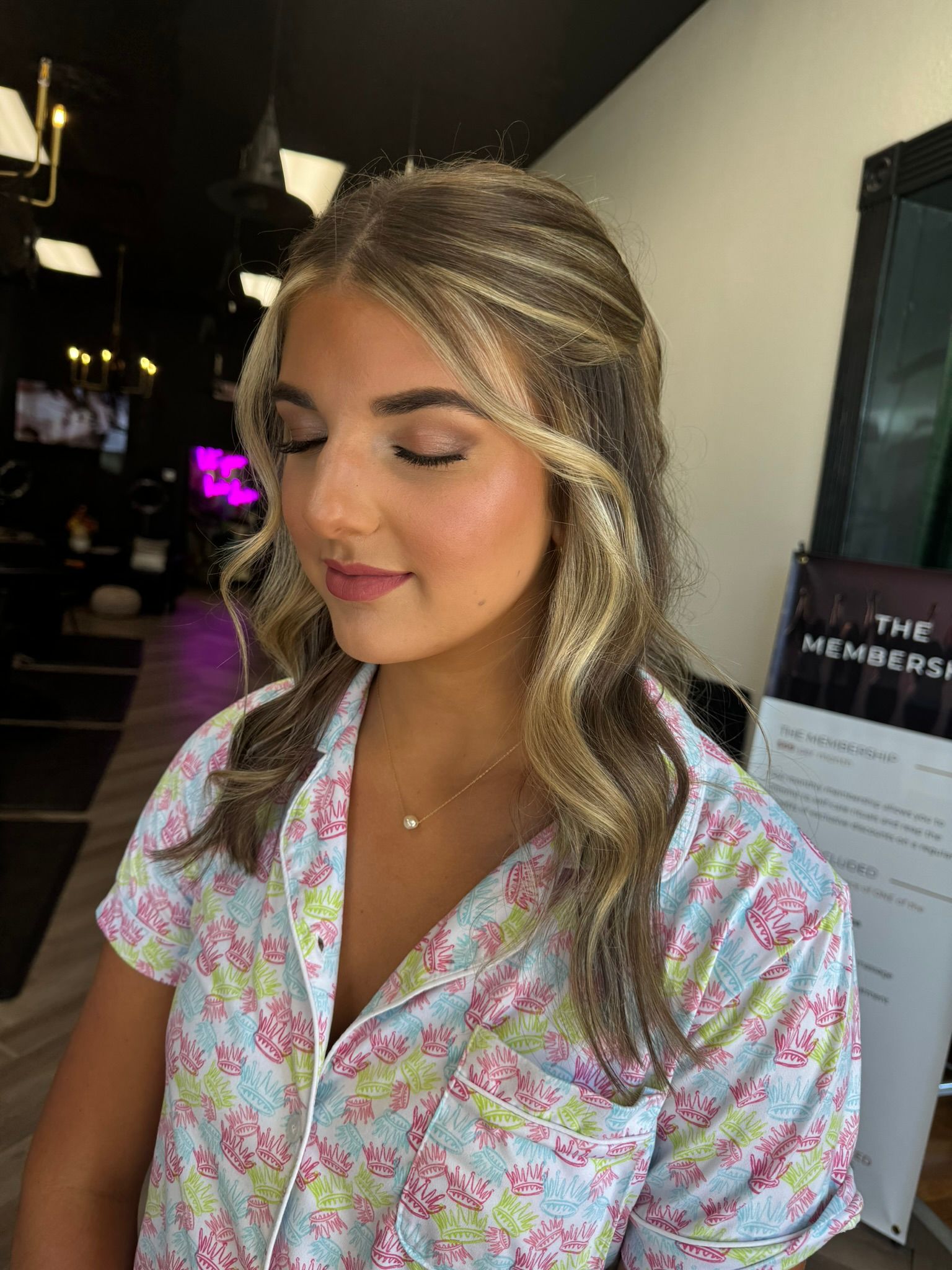 A woman in a floral shirt is getting her hair done in a salon