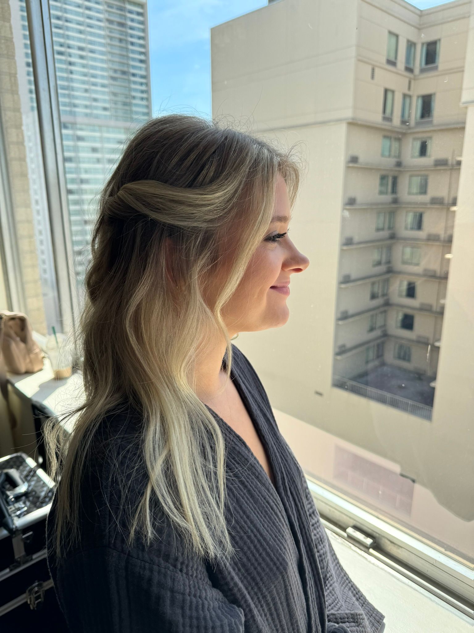A woman is standing in front of a window with a building in the background