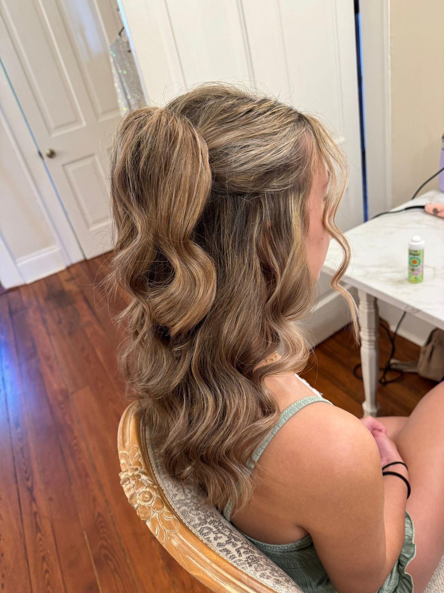 A woman is sitting in a chair with her hair in a half up half down hairstyle
