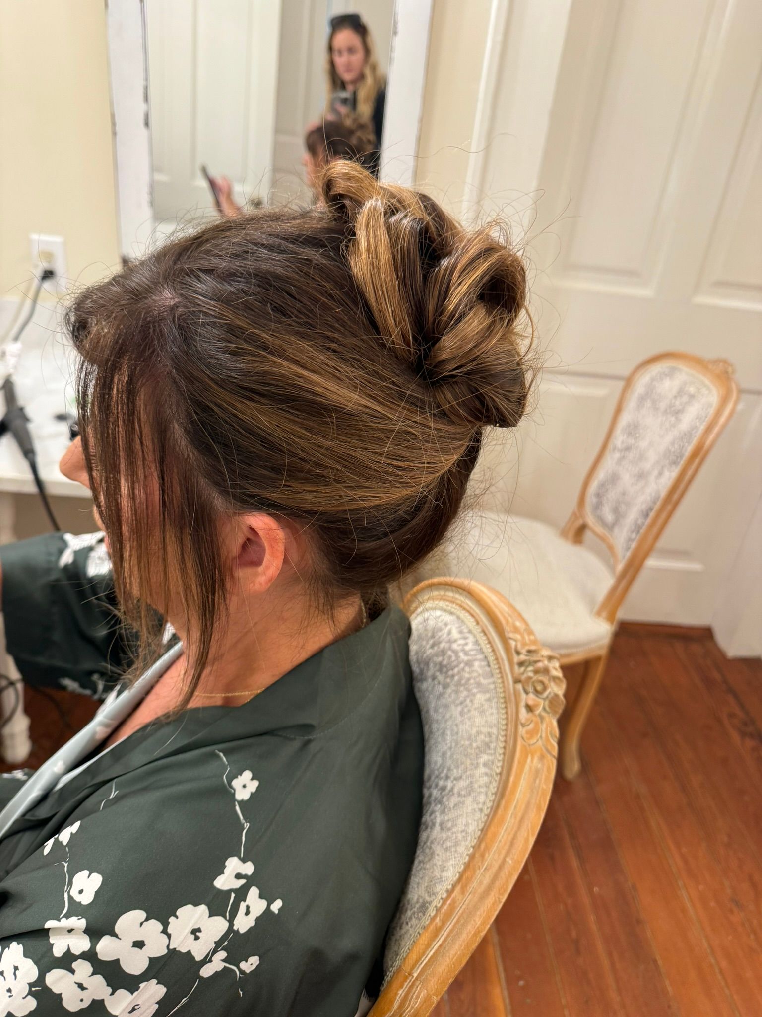 A woman is sitting in a chair with her hair in a bun