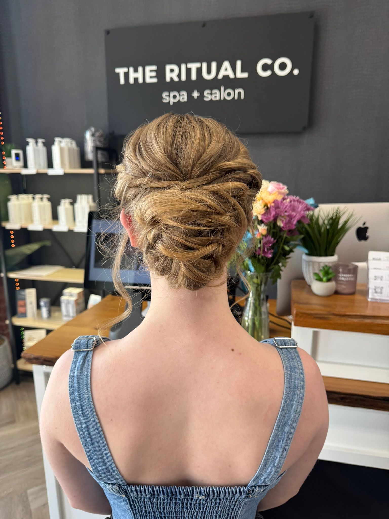 A woman is standing in front of a sign that says the ritual co. spa + salon