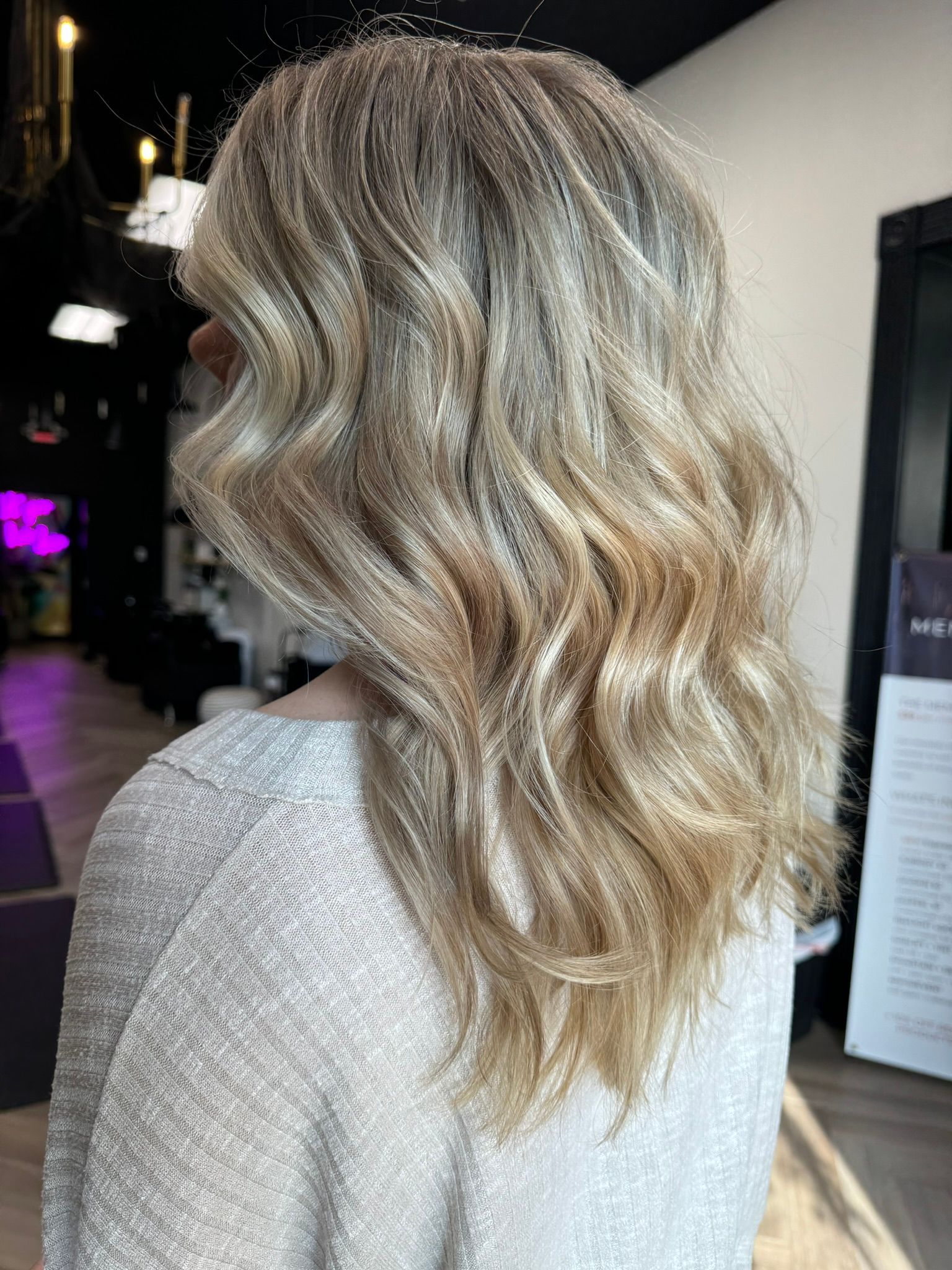 A woman with long blonde hair is standing in a salon