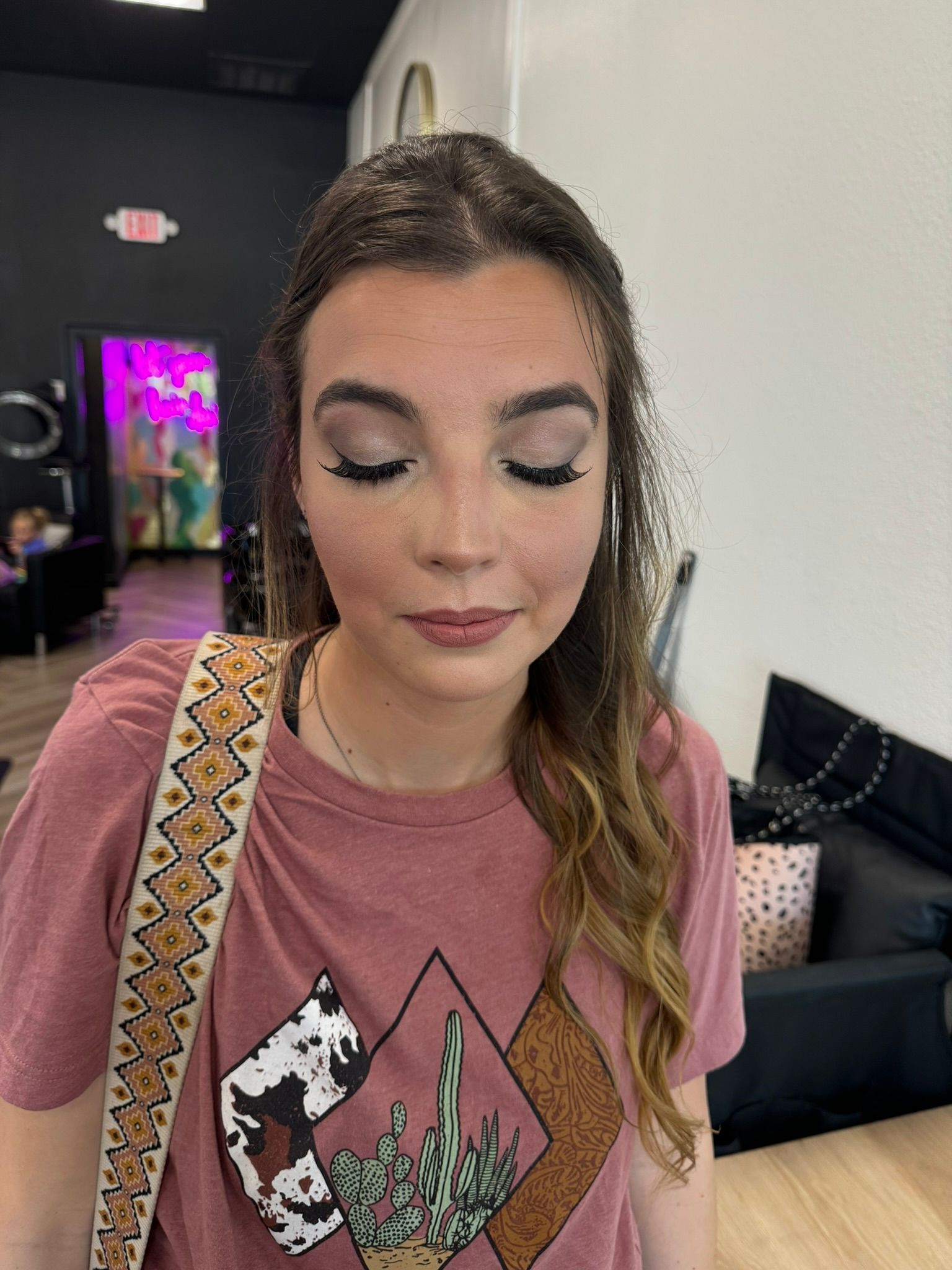 A woman wearing a pink t-shirt is standing in a room with her eyes closed
