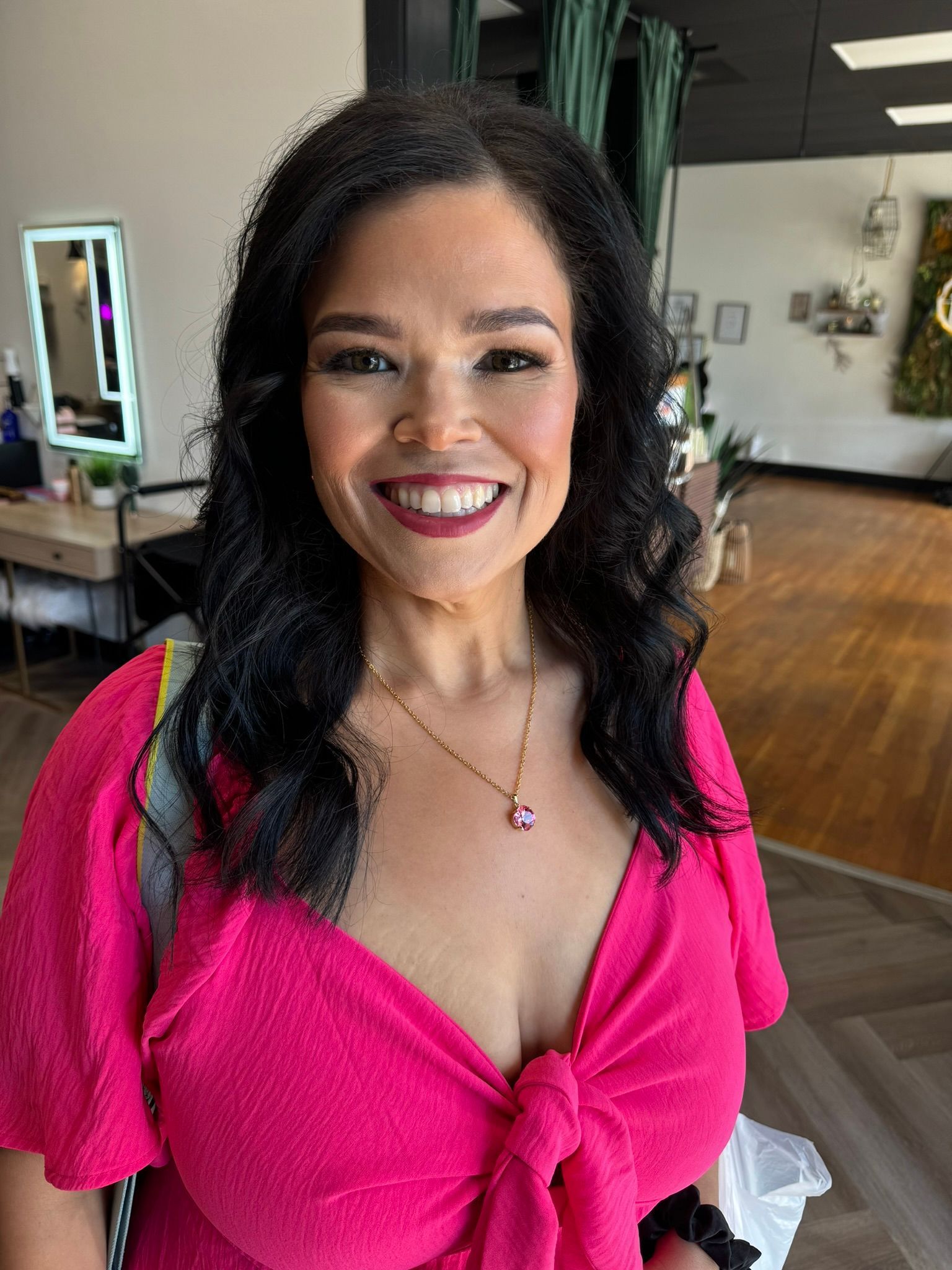 A woman in a pink dress is smiling in a room