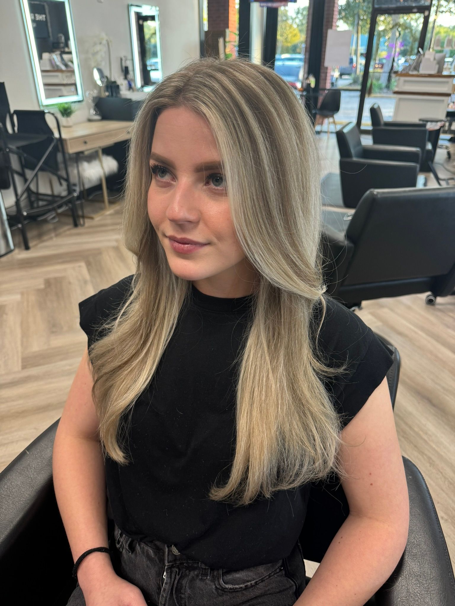 A woman with long blonde hair is sitting in a chair in a salon
