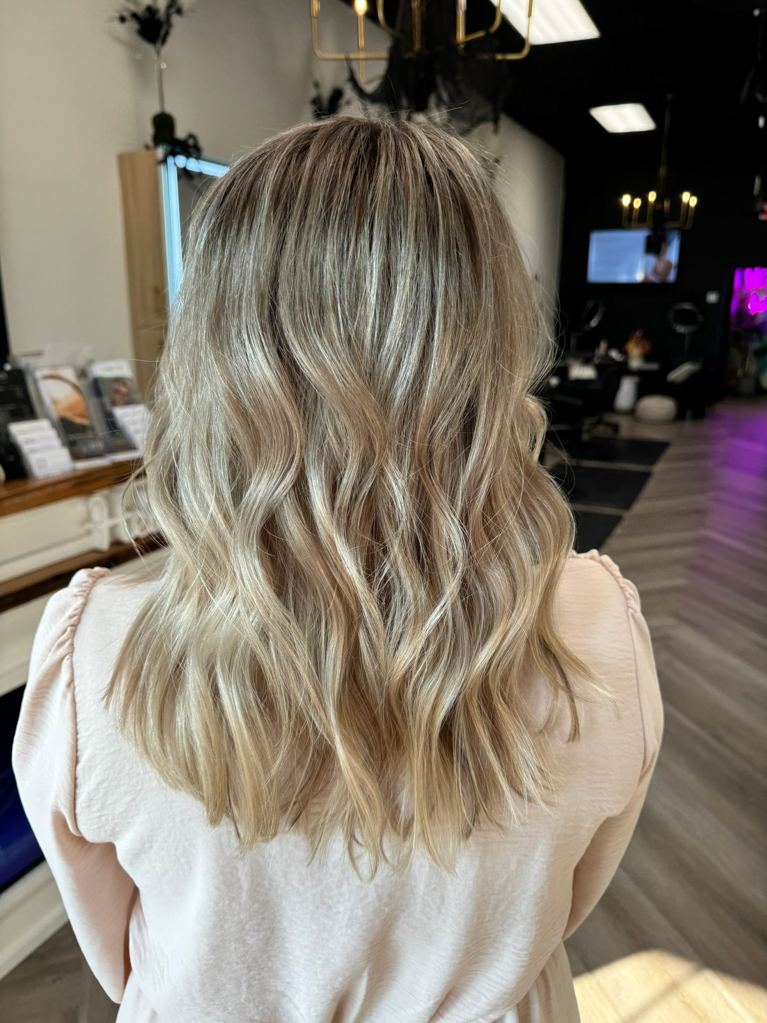 A woman with long blonde hair is standing in a salon