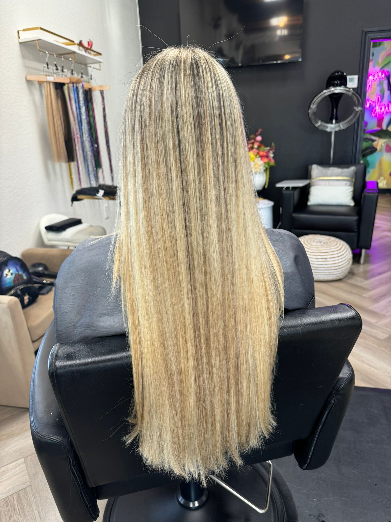 A woman with long blonde hair is sitting in a chair in a salon