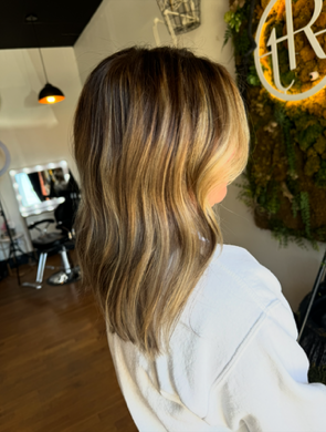 A woman with long hair is sitting in a chair in a salon