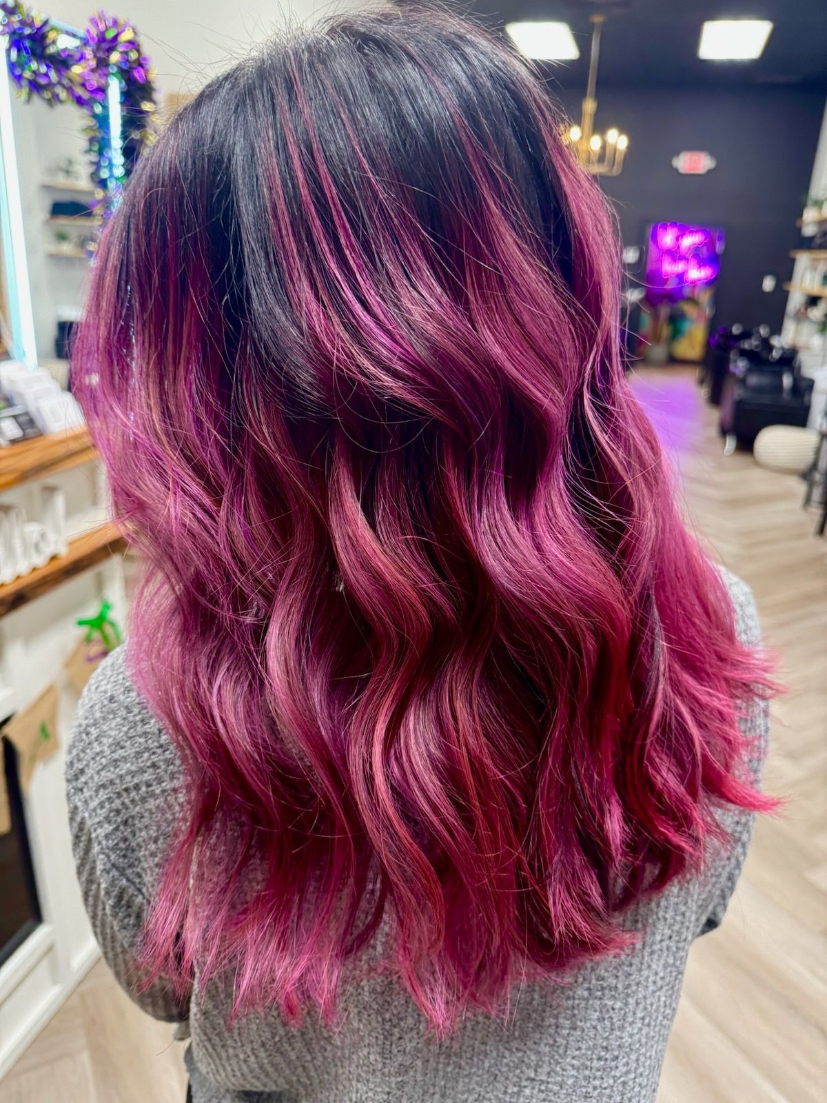 A woman with dark hair and pink hair is standing in a salon