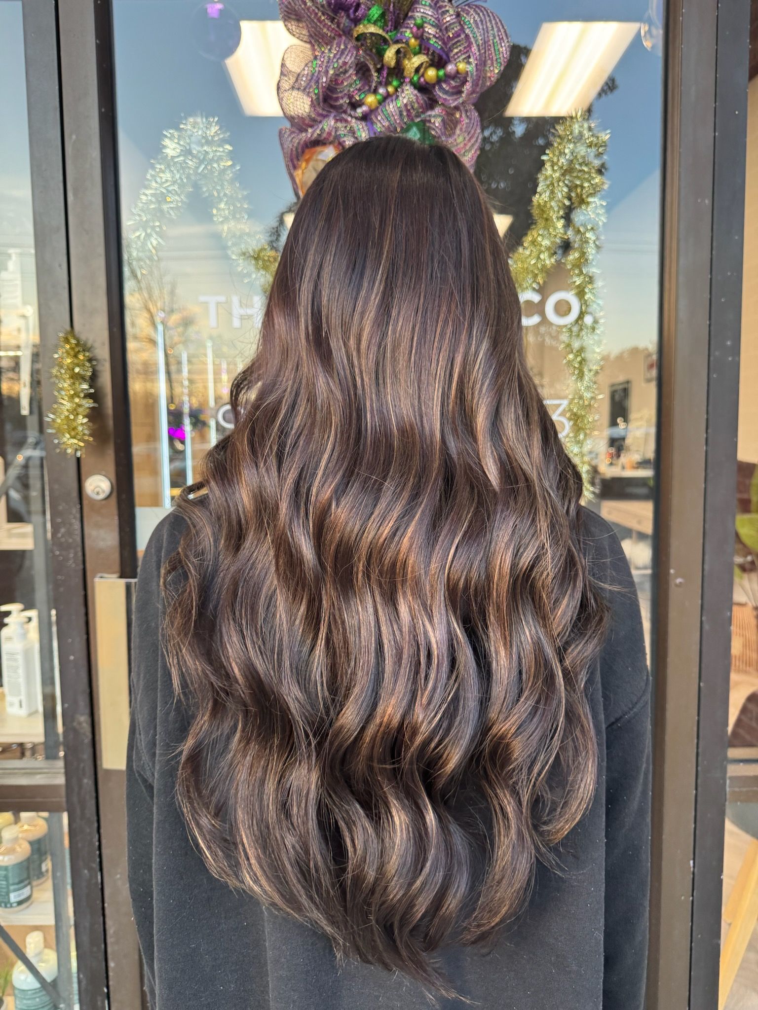 A woman with long dark hair is standing in front of a glass door