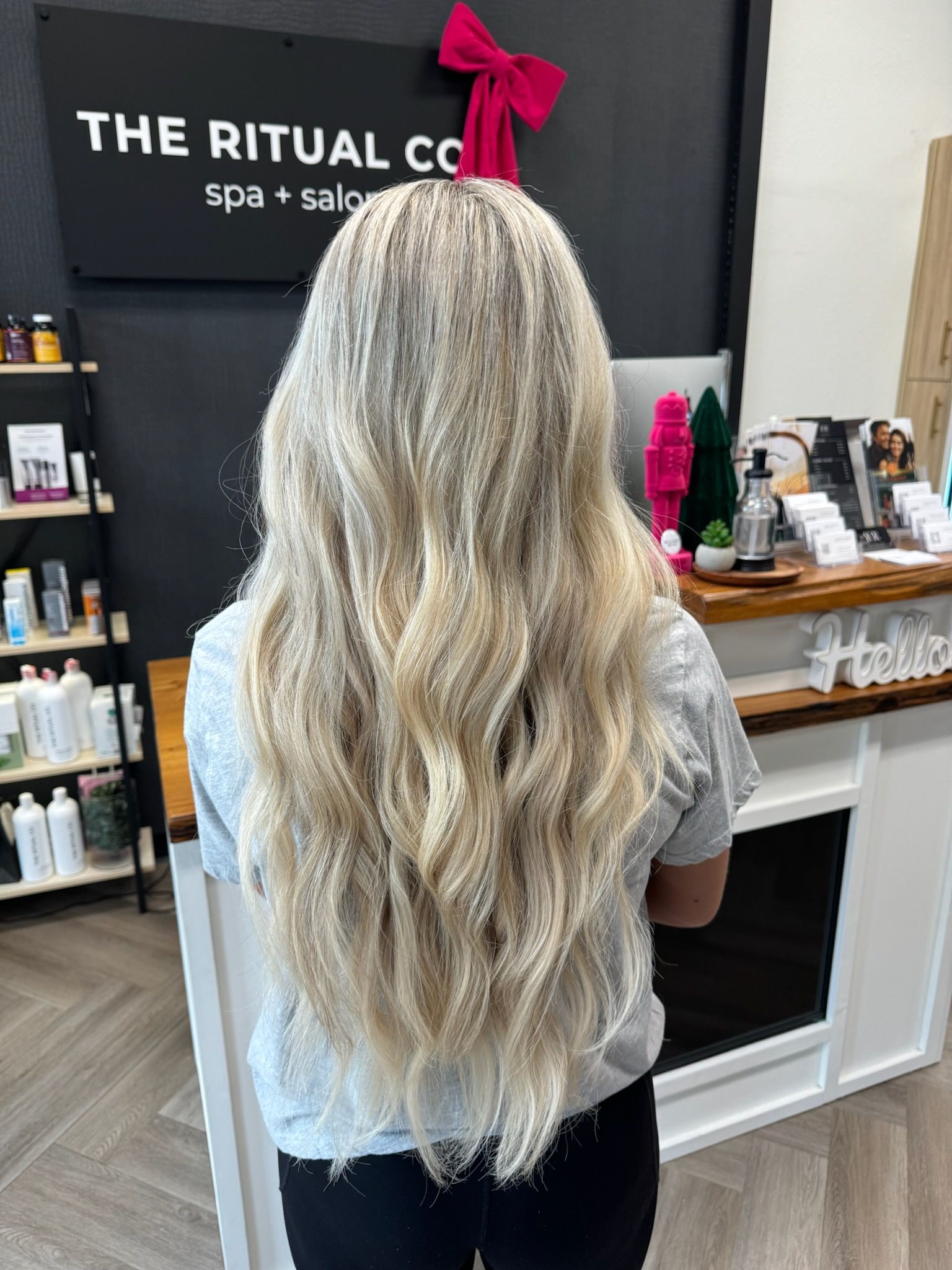 A woman with long blonde hair is standing in a salon