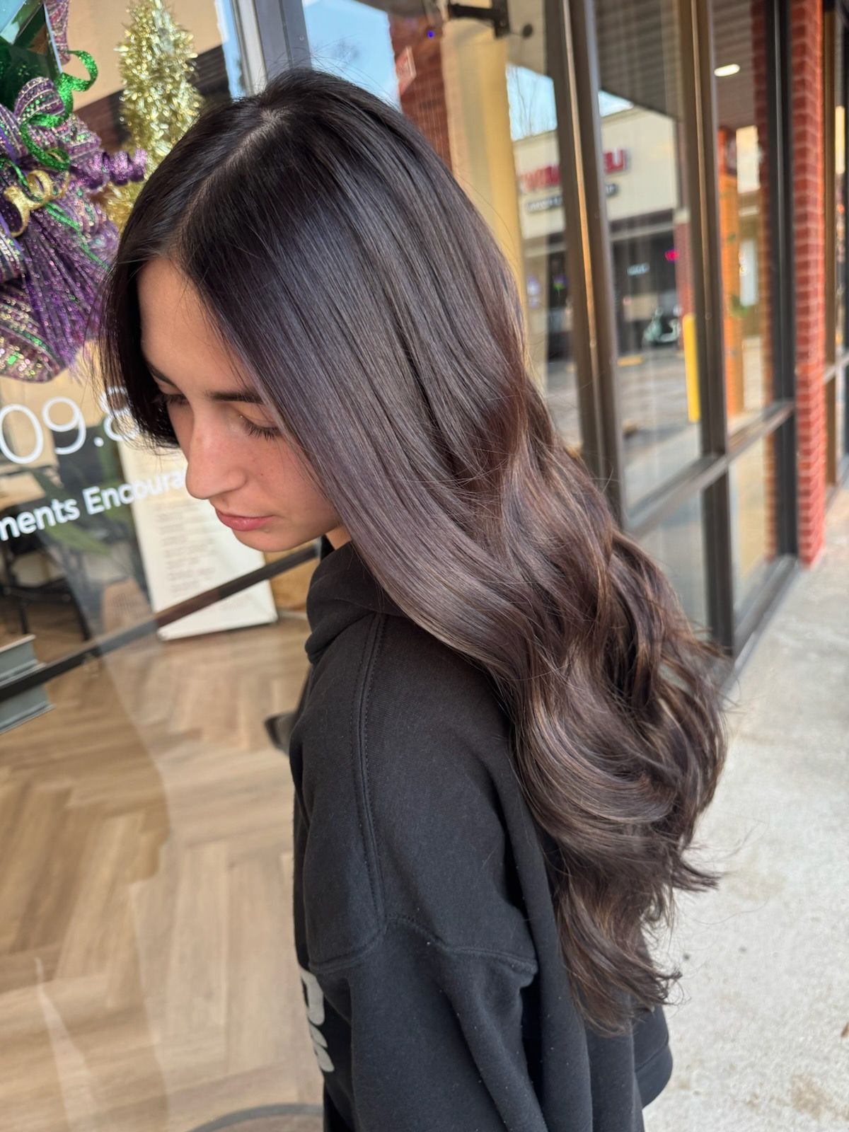 A woman with long dark hair is standing in front of a building