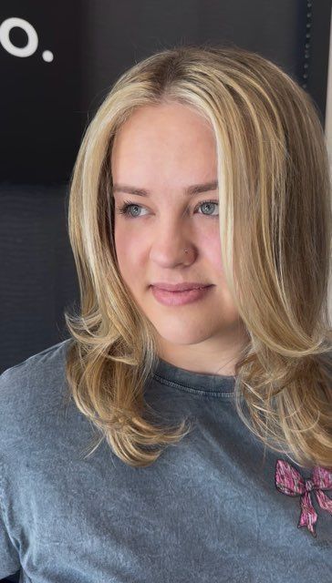 Blonde woman with fair skin and blue eyes smiles, looking slightly off-camera. Wearing gray shirt.