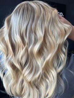 Blonde wavy hair, styled with highlights, a salon setting.