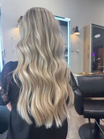 Blonde hair with wavy style. Woman in a salon with long blonde hair and highlights.