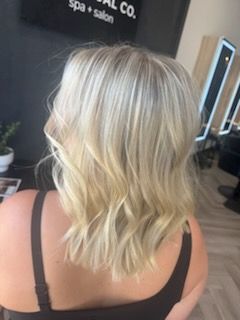 Woman with wavy, blonde hair, in a salon.