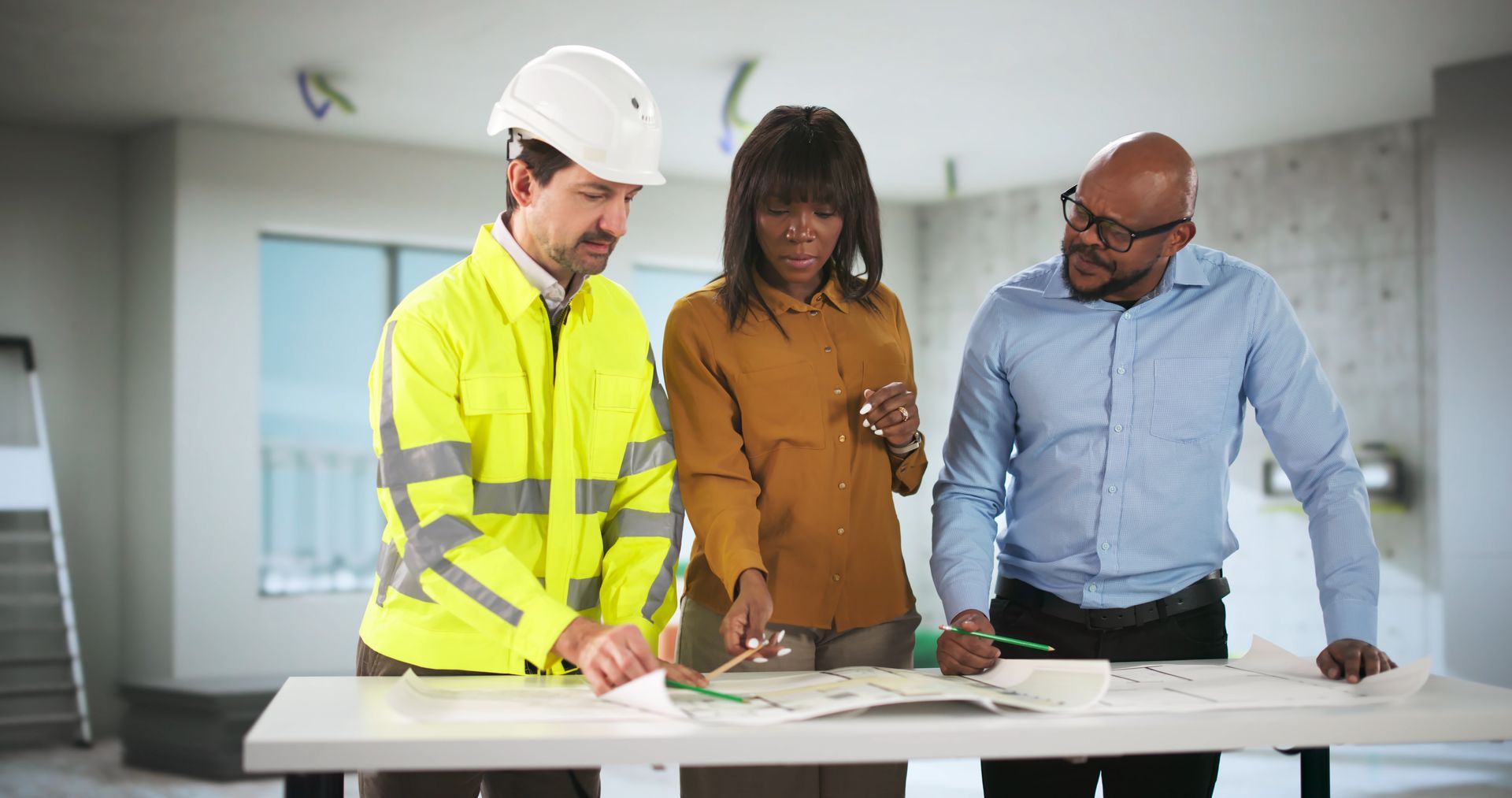 Young Engineer And Contractor Discussing House Plans With Couple.