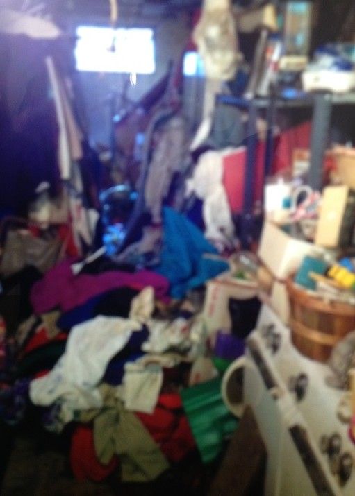 A messy room with a stove and a bunch of clothes