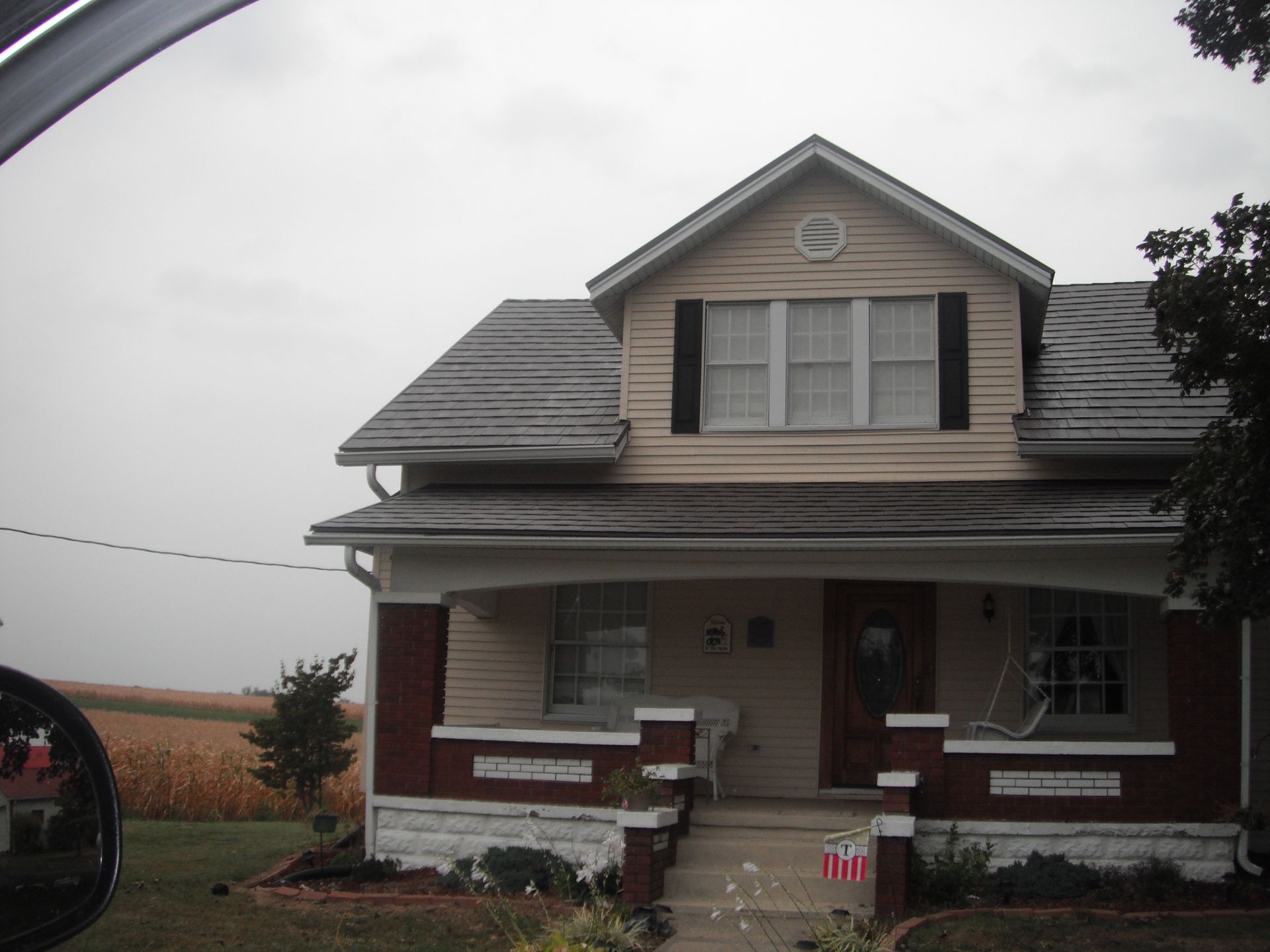 A house with a porch and a roof that is covered in shingles