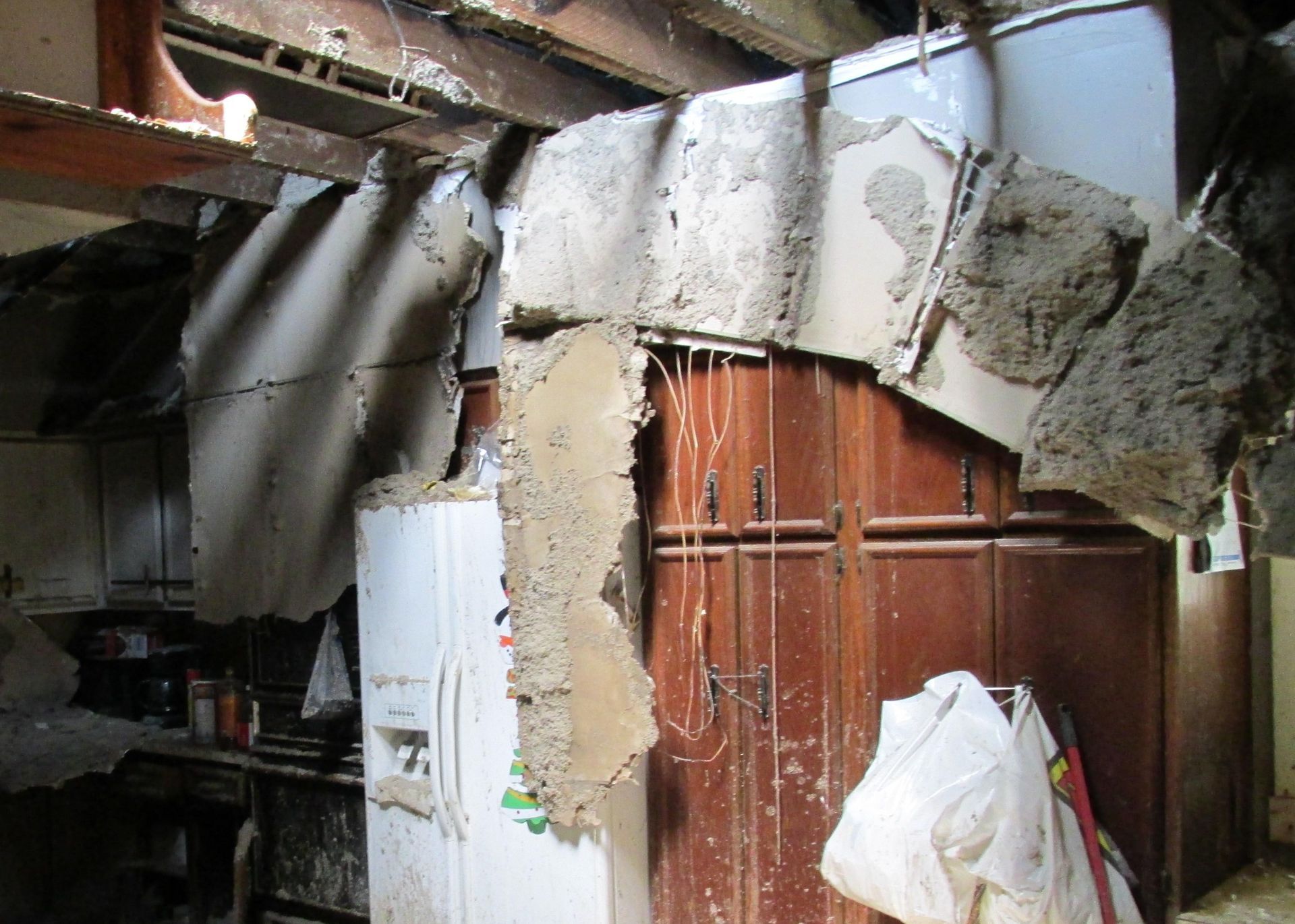 A kitchen with a broken wall and a bag hanging from the ceiling