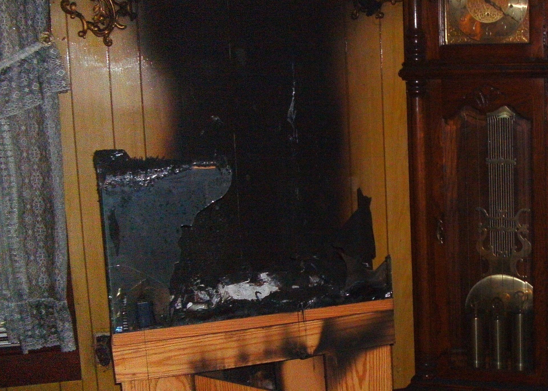 A room with a clock and a fireplace that has been damaged by fire