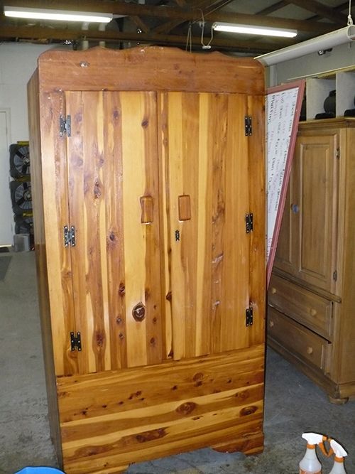 A wooden wardrobe is sitting in a room next to spray bottles