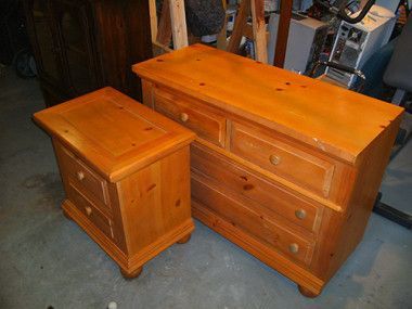 A wooden dresser and nightstand are sitting on a carpeted floor.