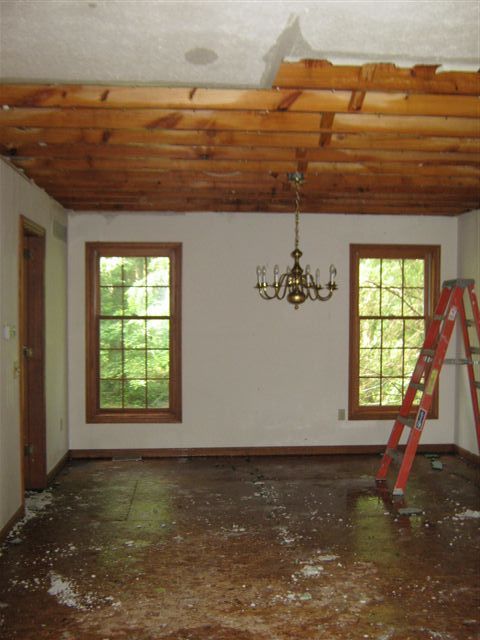 An empty room with a ladder and a chandelier hanging from the ceiling