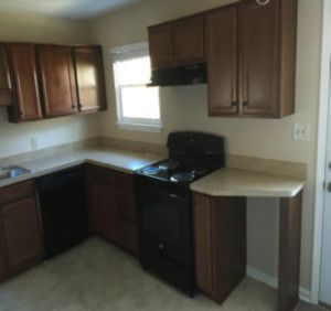 A kitchen with a stove, dishwasher, sink and cabinets.