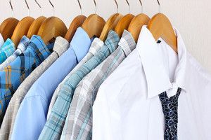 A row of shirts and ties hanging on wooden hangers.