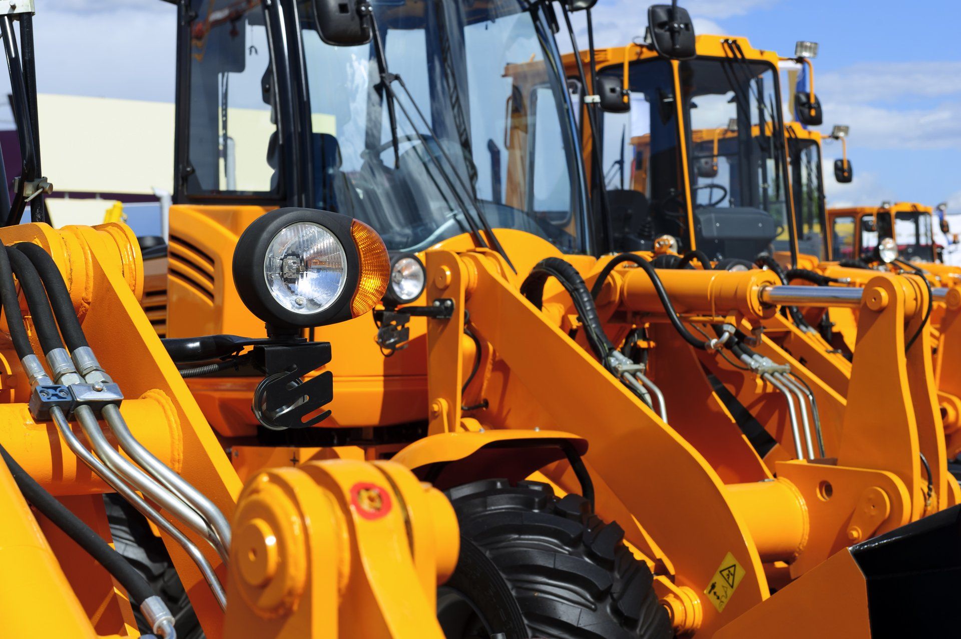 Bulldozer headlight, row of huge orange powerful construction machines, tractors, excavators