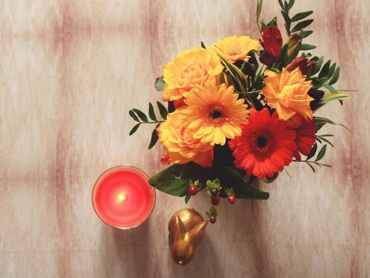 Cheerful orange and red flowers arranged near a burning candle, cremation services Phoenix, AZ