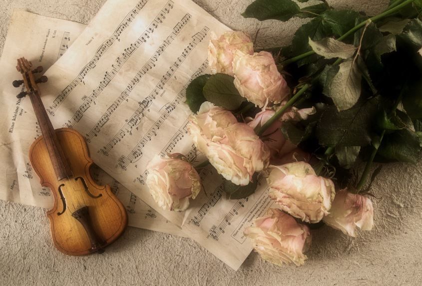 Violin on sheet music with pale roses, heartfelt funeral songs, funeral homes Phoenix, AZ