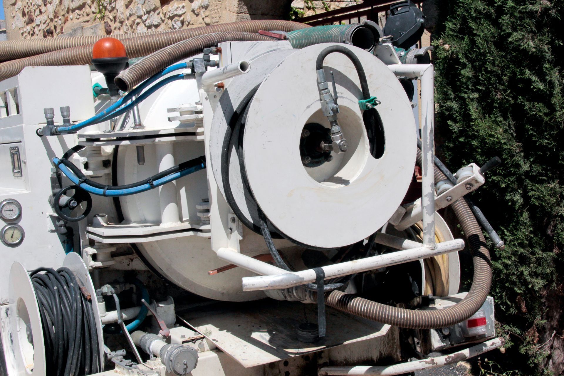 White truck-mounted sewer cleaning equipment with coiled hose reel and various tubes.