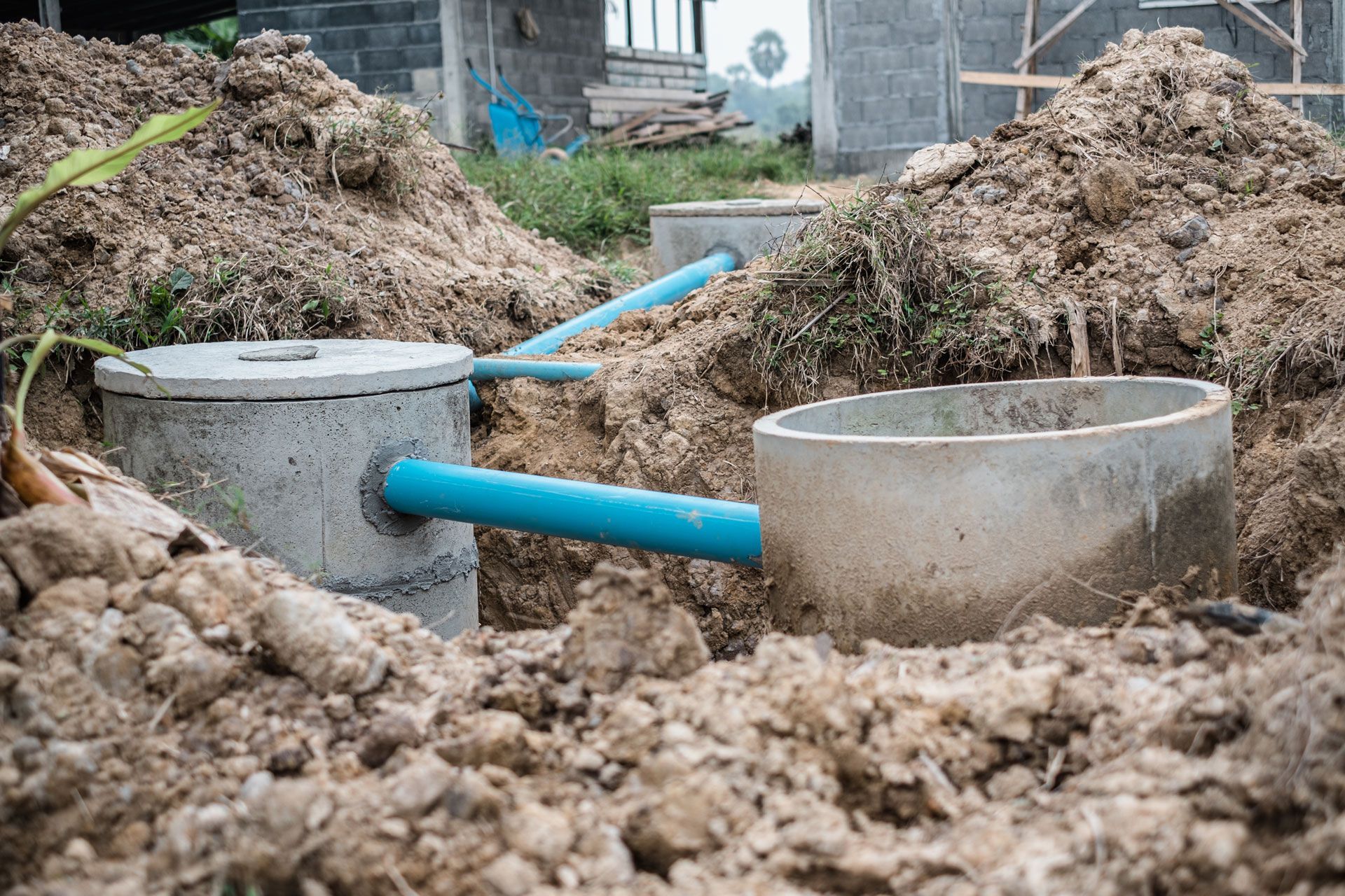 Septic tanks and blue pipes installed in dirt. Construction site outdoors.