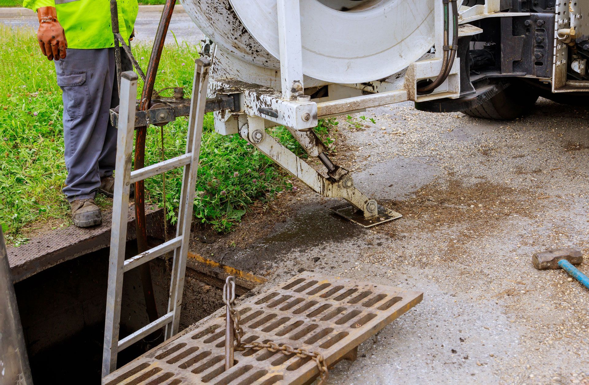 Concrete being poured into a sewer, worker in high-vis vest and boots stands near ladder.