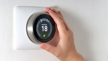 A person is adjusting a thermostat on a wall.
