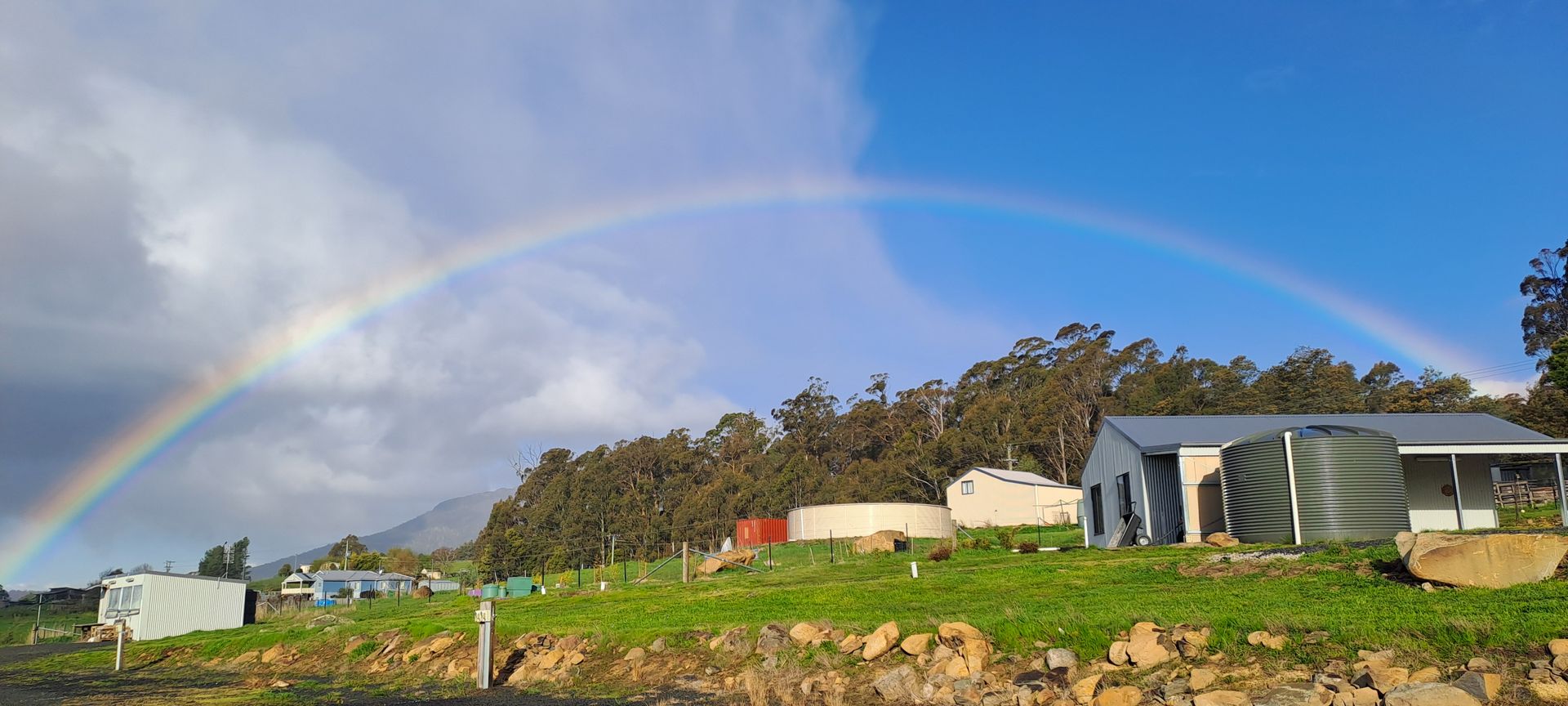 A large grassy field with a fence in the foreground and a building in the background.
