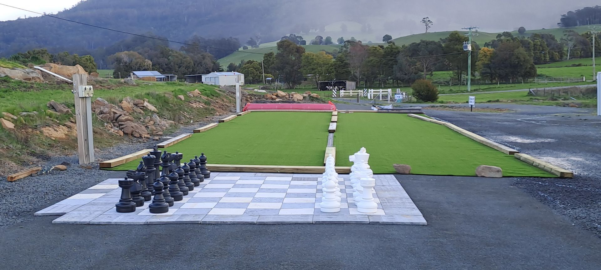 A large chess board is in the middle of a grassy field
