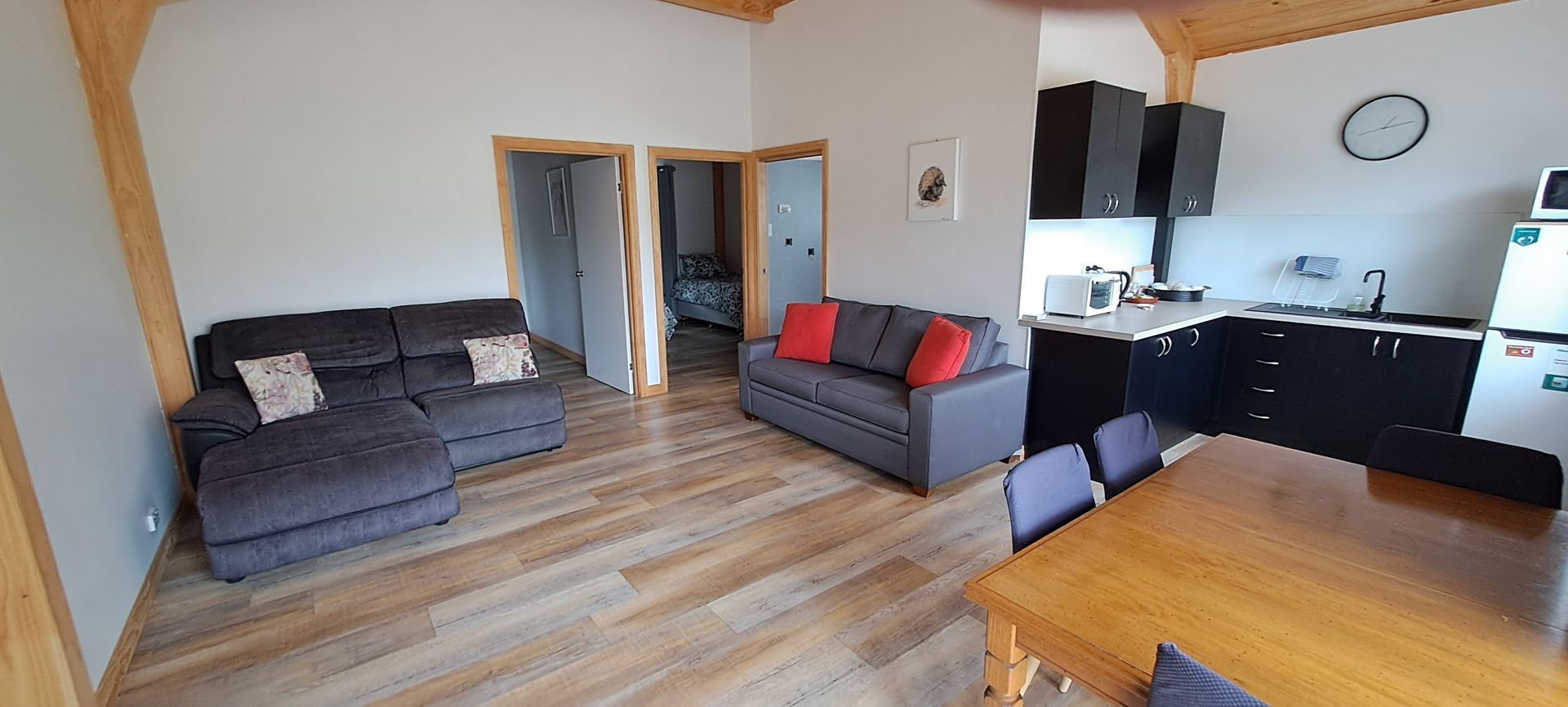 A living room with a couch , table , chairs and a kitchen.