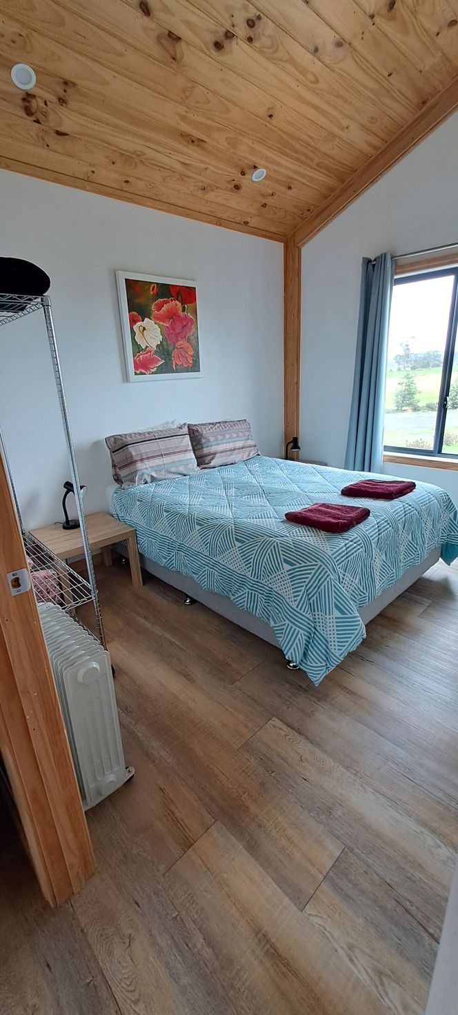 A bedroom with a large bed and a wooden ceiling.