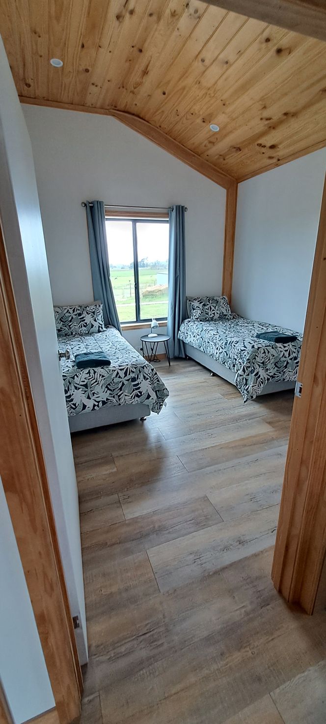 A bedroom with two beds and a wooden ceiling.