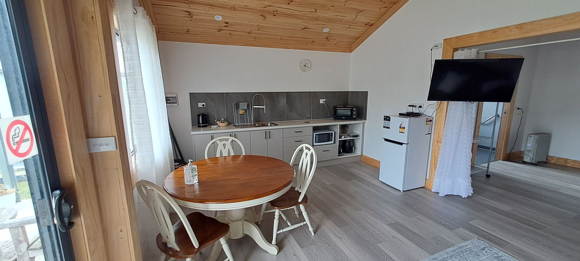 A living room with a table and chairs and a flat screen tv.