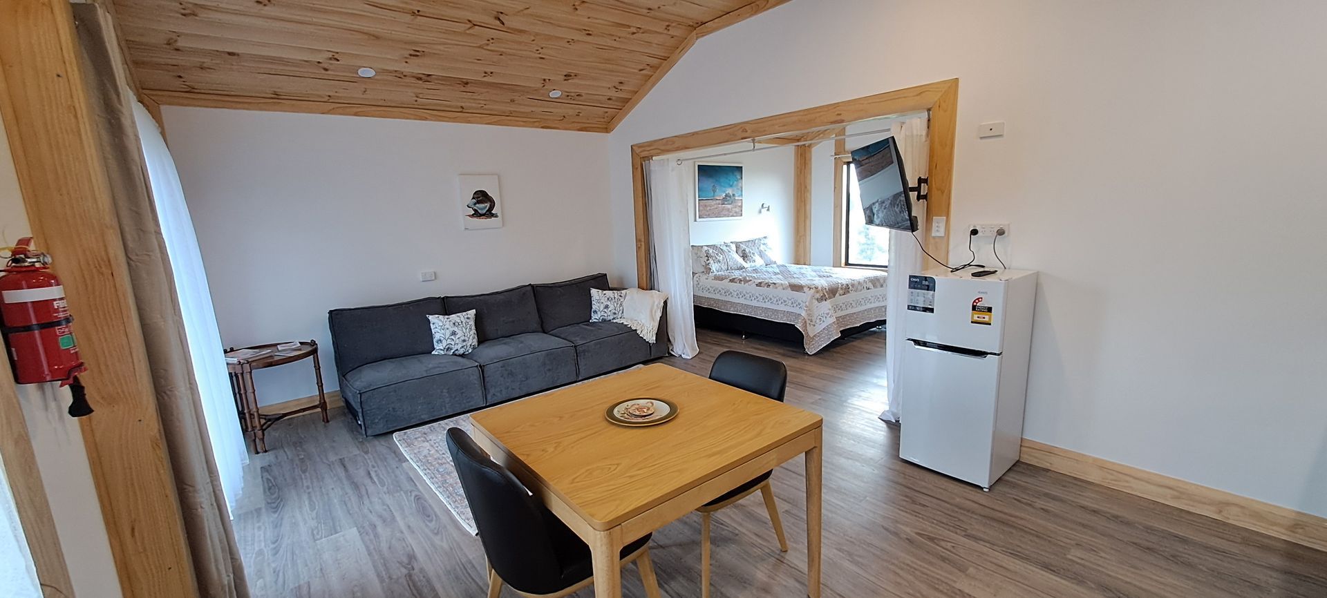 A living room with a couch , table , chairs and a refrigerator.