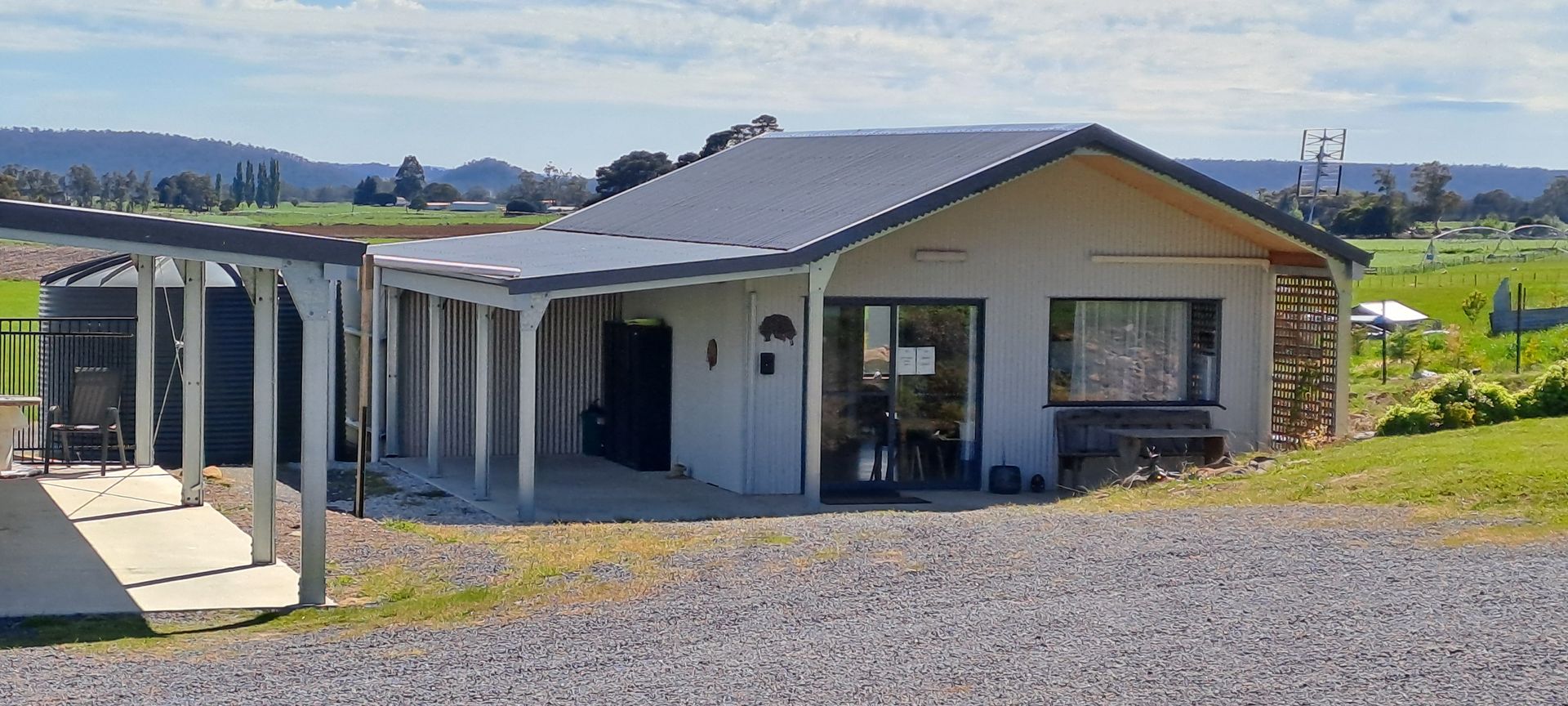 A small white house with a porch and a bench in front of it.
