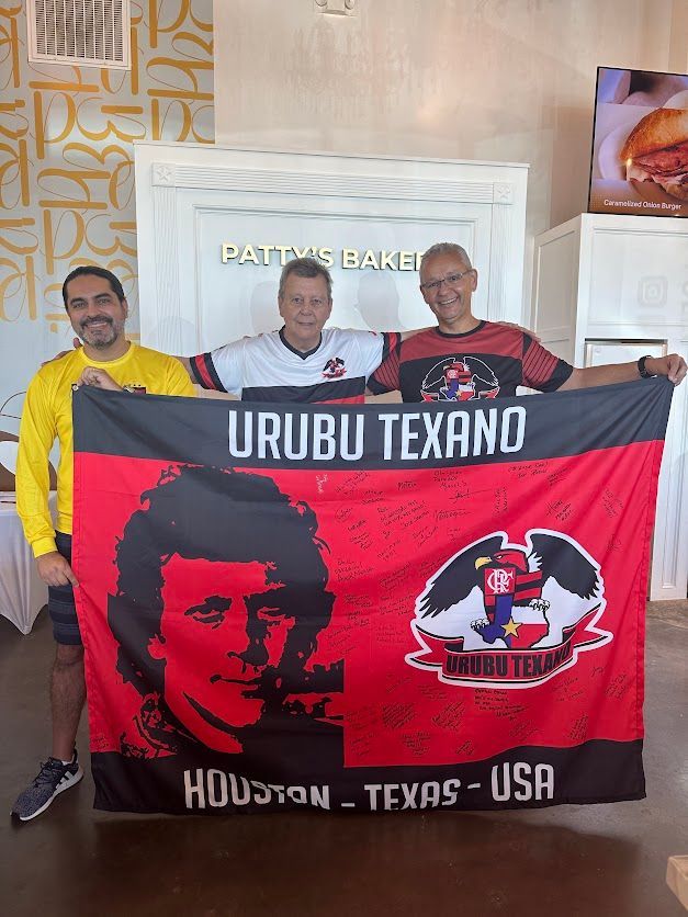 Three men are holding a flag that says urubu texano houston texas usa.