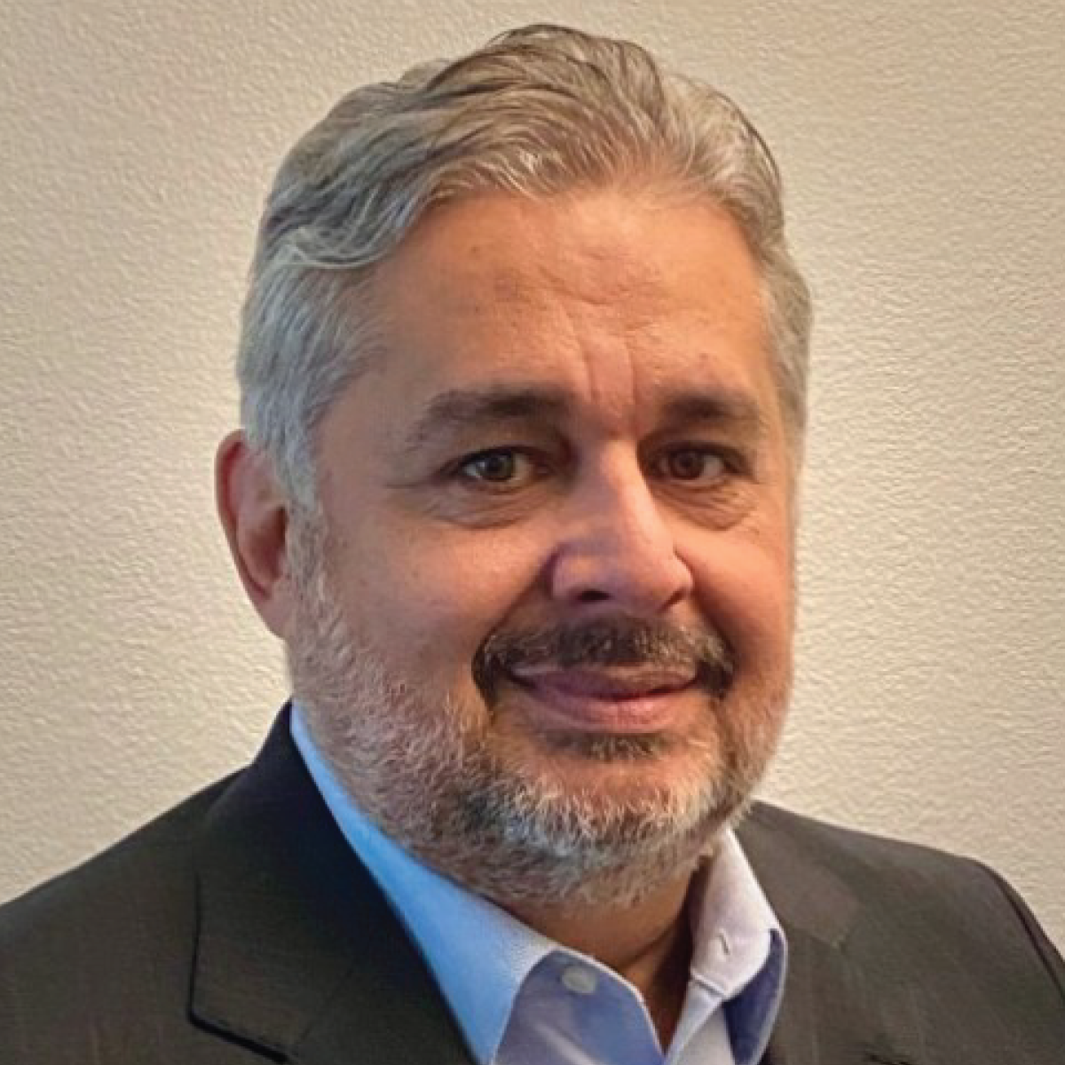 A man with a beard is wearing a suit and smiling for the camera.