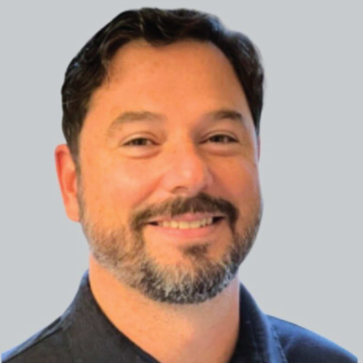 A man with a beard and mustache is smiling for the camera.