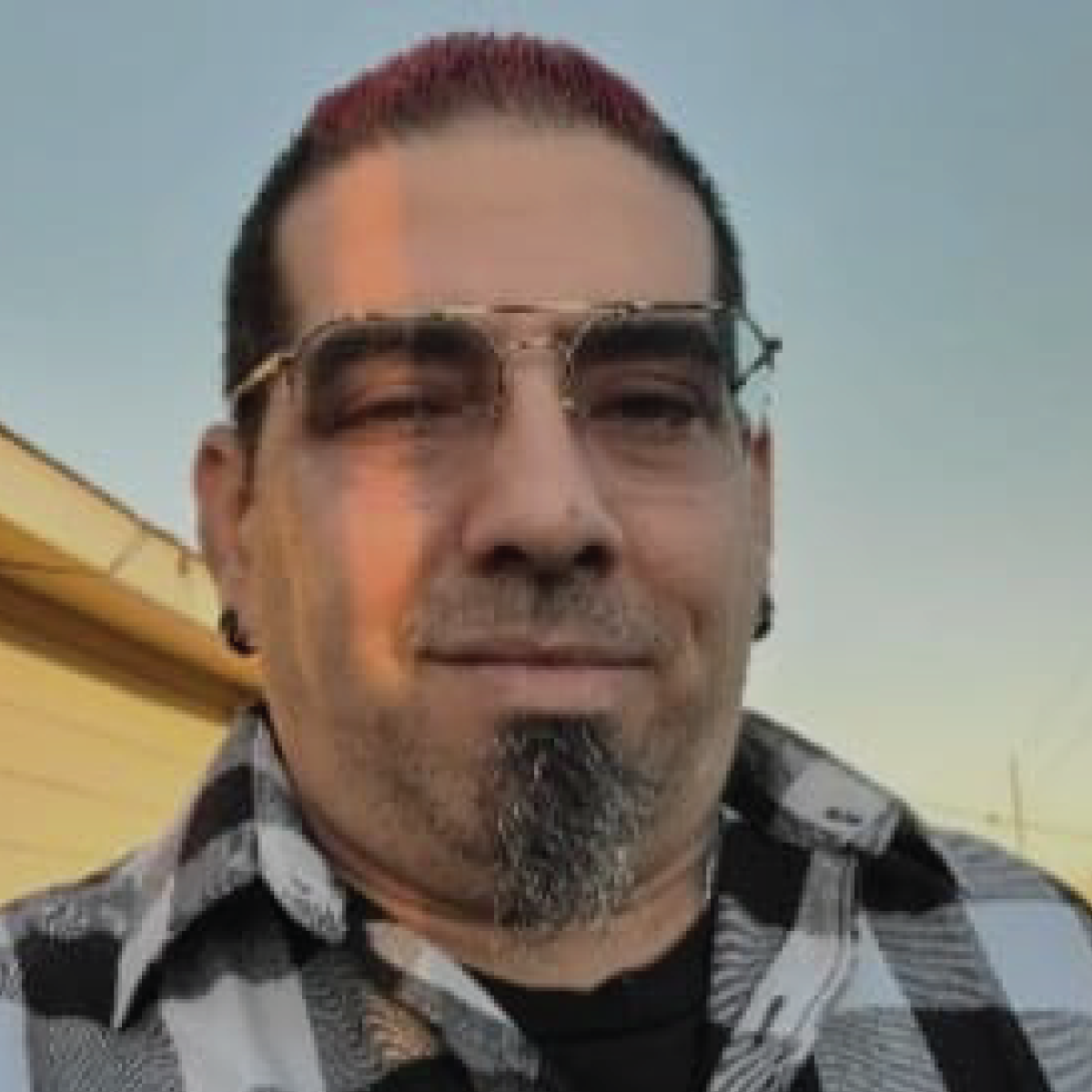 A man with a beard and glasses is wearing a plaid shirt.