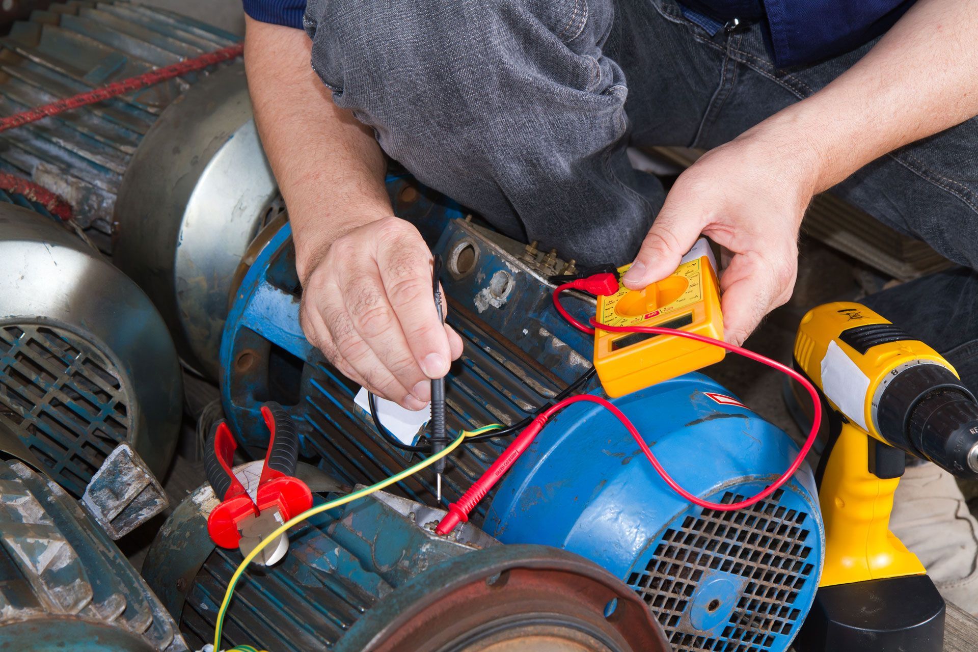 A man is working on an electric motor with a drill.
